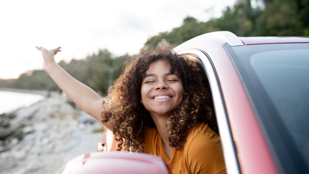 <p>Mujer viajando en auto sonriendo</p>